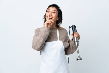 Şef Uruguaylı kız izole edilmiş beyaz arka plan üzerinde el blenderi kullanarak sessizlik hareketi yapıyor.