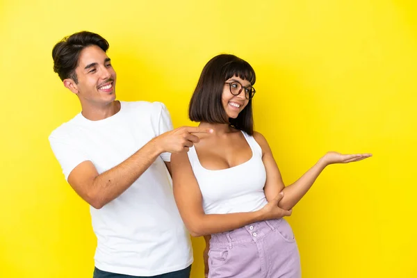 Giovane Coppia Mista Isolato Sfondo Giallo Puntando Indietro Presentando Prodotto — Foto Stock