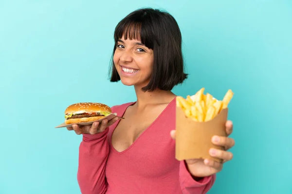 Joven Morena Sosteniendo Hamburguesa Patatas Fritas Sobre Fondo Azul Aislado — Foto de Stock