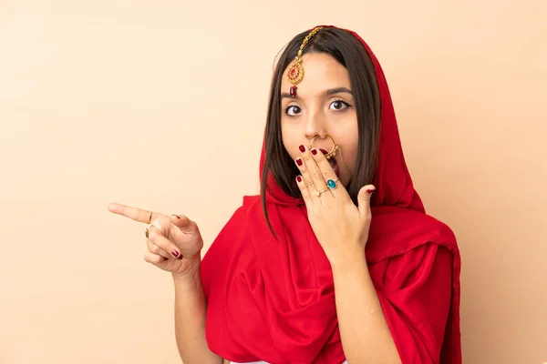 若いですインドの女性はサイドを指している間驚きの表現とベージュの背景に隔離 — ストック写真