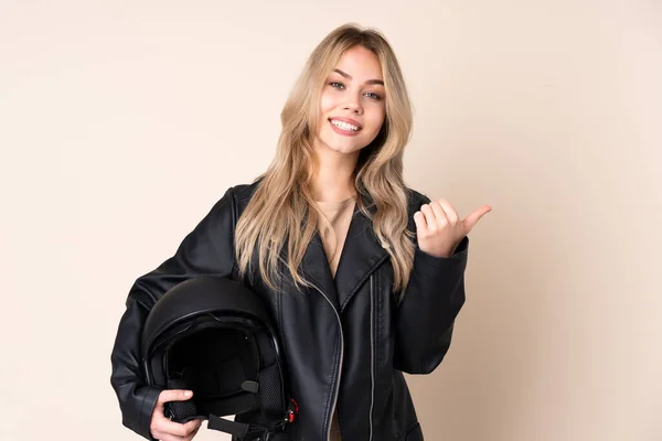 오토바이 헬멧을 러시아 소녀가 엄지손가락을 치켜들고 미소를 베이지 배경으로 고립되어 — 스톡 사진