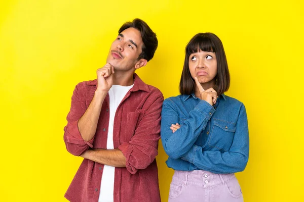 Junges Mischlingspaar Isoliert Auf Gelbem Hintergrund Und Denkt Beim Nachschauen — Stockfoto