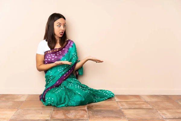 年轻的印度女人坐在地板上 面带微笑地看着旁边 — 图库照片