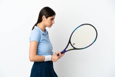 Beyaz arka planda tenis oynayan beyaz tenli genç kadın.