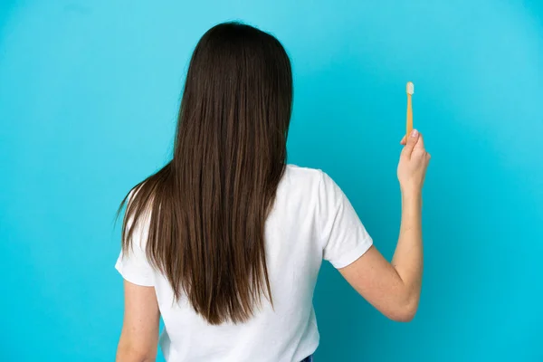 年轻的高加索女人在后背的蓝色背景上独立刷牙 — 图库照片