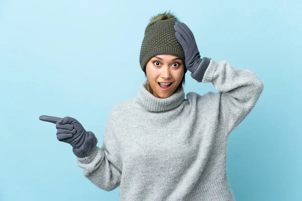 Jovem Uruguaia Com Chapéu Inverno Isolado Fundo Azul Surpreso Apontando — Fotografia de Stock