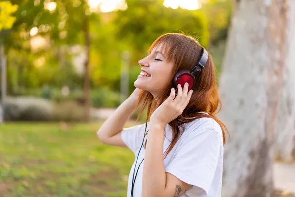 Νέα Όμορφη Κοκκινομάλλα Γυναίκα Εξωτερικούς Χώρους Ακούγοντας Μουσική — Φωτογραφία Αρχείου