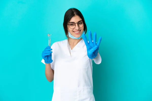 Junge Kaukasische Zahnärztin Frau Hält Werkzeuge Isoliert Auf Blauem Hintergrund — Stockfoto