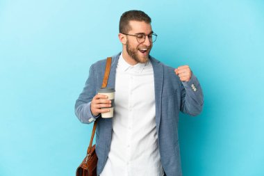 Kafkasyalı genç işadamı mavi arka planda izole bir şekilde zaferi kutluyor.