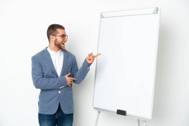 Beyaz arka planda izole edilmiş beyaz panoda sunum yapan genç bir iş kadını...