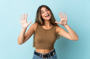 Mavi arka planda izole edilmiş genç beyaz kadın parmaklarıyla ona kadar sayıyor.