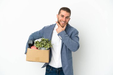 Beyaz arka planda izole edilmiş şeylerle dolu bir kutuyu alırken mutlu ve gülümseyen genç Kafkasyalı hamle yapıyor.