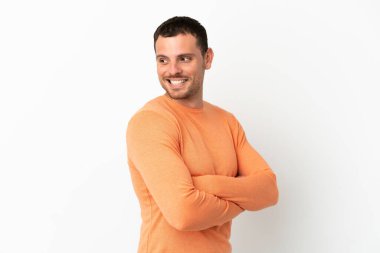 İzole edilmiş beyaz arka planı olan Brezilyalı bir adam yana bakıyor ve gülümsüyor.