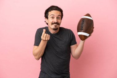 Genç beyaz adam rugby oynuyor. Pembe arka planda izole edilmiş. Para hareketi yapıyor.