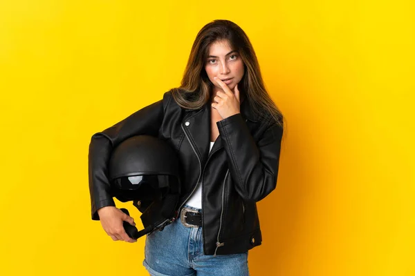 黄色の背景思考で隔離されたオートバイのヘルメットを持っている女性 — ストック写真