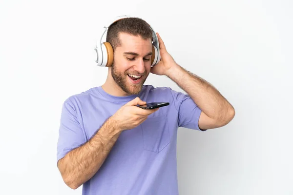 Νεαρός Όμορφος Καυκάσιος Άνδρας Απομονωμένος Λευκό Φόντο Ακούγοντας Μουσική Κινητό — Φωτογραφία Αρχείου