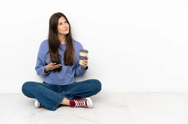 Jovem Mulher Sentada Chão Segurando Café Para Levar Celular Enquanto — Fotografia de Stock