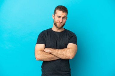 Mavi arka planda izole edilmiş yakışıklı beyaz bir adam üzgün hissediyor.