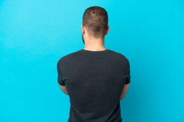 Genç, yakışıklı, beyaz bir adam arka planda mavi arka planda izole edilmiş.