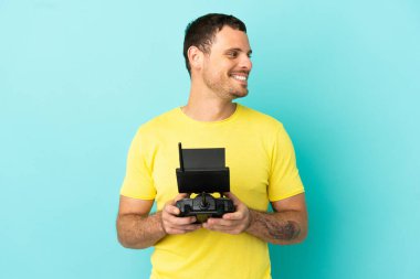 Brezilyalı adam uzaktan kumandalı uzaktan kumandayla izole edilmiş mavi arka plan görünümlü