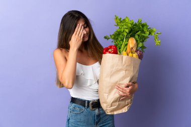 Market poşeti taşıyan genç bir kadın yorgun ve hasta bir ifadeyle