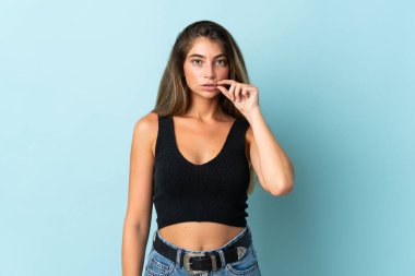 Mavi arka planda izole edilmiş beyaz bir kadın sessizlik işareti gösteriyor.