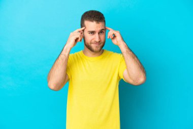 Mavi arka planda soyutlanmış yakışıklı, beyaz bir adam. Şüpheleri ve düşünceleri var.