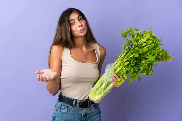 Giovane Donna Che Tiene Sedano Isolato Sfondo Viola Facendo Dubbi — Foto Stock