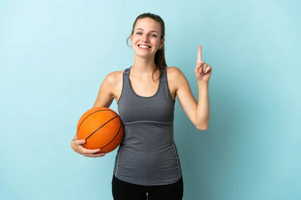 Jovem Mulher Jogando Basquete Isolado Fundo Azul Apontando Para Uma — Fotografia de Stock