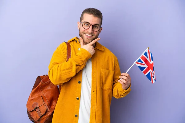 Mladý Běloch Drží Vlajku Spojeného Království Izolované Fialovém Pozadí Šťastný — Stock fotografie