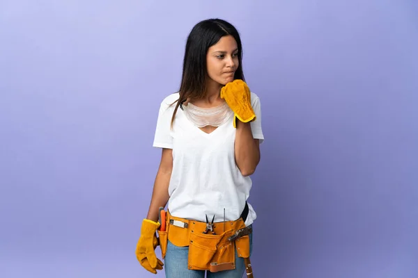 Young electrician woman isolated on purple background having doubts