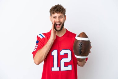 Beyaz arka planda ragbi oynayan genç beyaz bir adam şaşırmış ve şok olmuş bir yüz ifadesiyle izole edilmiş.