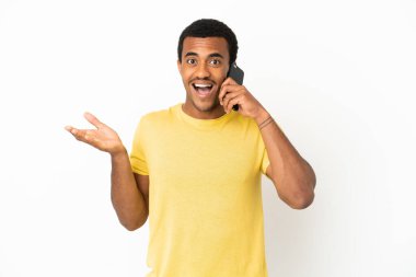 Yüzünde şok ifadesi olan, izole edilmiş beyaz arka plan üzerinden cep telefonu kullanan Afro-Amerikalı yakışıklı bir adam.