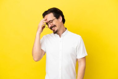 Sarı arka planda izole edilmiş genç beyaz adam gülüyor.