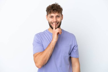 Beyaz arka planda izole edilmiş yakışıklı beyaz adam sessiz bir jest işareti gösteriyor. Parmağını ağzına sokuyor.