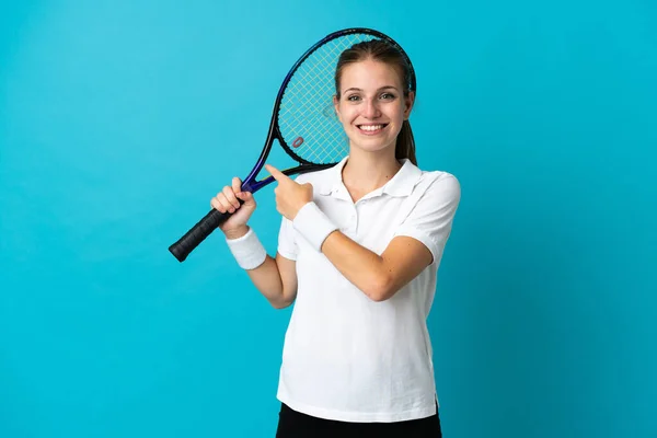プロダクトを提示する側を指す青の背景に隔離された若い女性テニス選手 — ストック写真