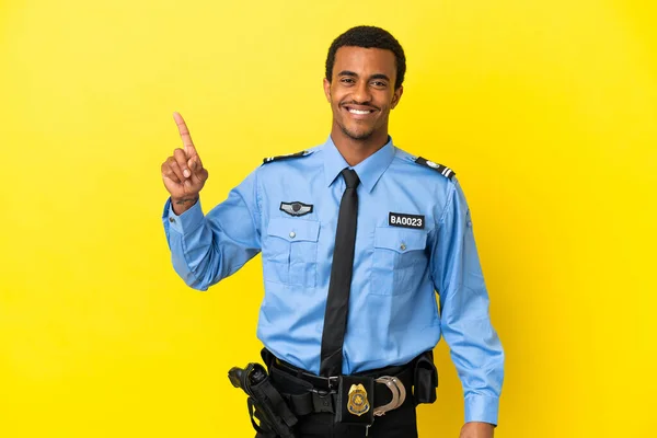 African American police man over isolated yellow background pointing up a great idea