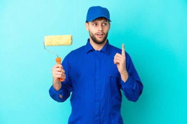 Kafkasyalı ressam, mavi arka planda izole edilmiş bir şekilde parmağı yukarı çeken bir fikir düşünüyor.