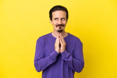 Genç beyaz adam sarı arka planda izole edilmiş bir şeyler çeviriyor.