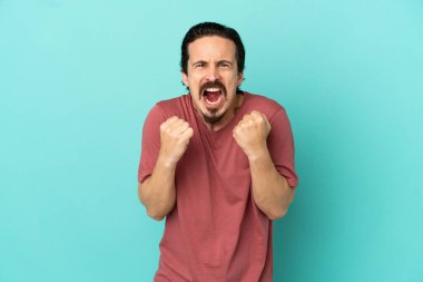 Kafkasyalı genç adam mavi arka planda izole edilmiş. Kötü bir durum yüzünden hayal kırıklığına uğramış.