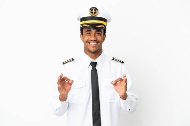 İzole edilmiş beyaz arka planda Afro-Amerikan uçak pilotu parmaklarıyla tamam işareti gösteriyor.