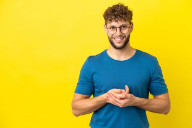 Sarı arka planda izole edilmiş yakışıklı beyaz adam gülüyor.