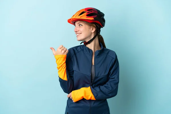 Молодая Женщина Велосипедист Изолированы Синем Фоне Указывая Сторону Представить Продукт — стоковое фото