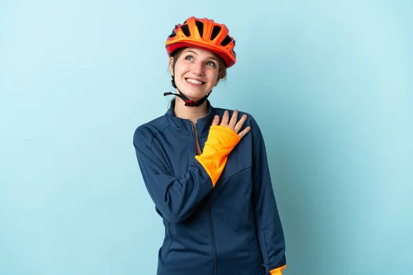Молода Жінка Велосипедистка Ізольована Синьому Фоні Дивлячись Вгору Посміхаючись — стокове фото