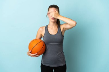 Basketbol oynayan genç bir kadın mavi arka planda tek başına, gözleri elleriyle kapatıyor. Bir şey görmek istemiyorum.