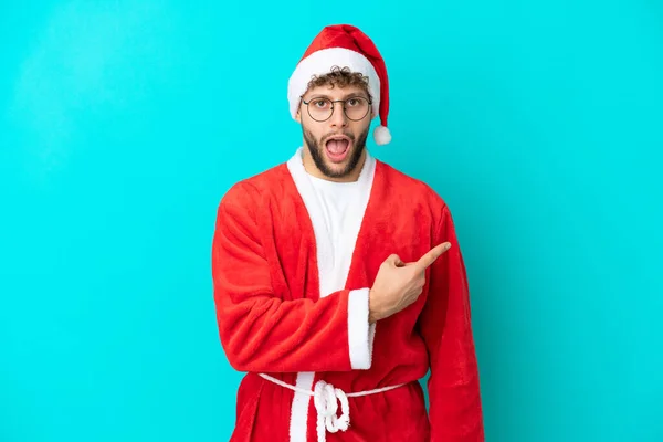 Joven Disfrazado Santa Claus Aislado Sobre Fondo Azul Sorprendido Señalando —  Fotos de Stock