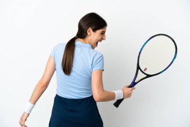 Beyaz arka planda izole edilmiş genç beyaz kadın tenis oynuyor ve zaferi kutluyor.