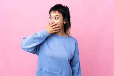 Genç Uruguaylı kadın pembe arka planda, yan tarafa bakarken sürpriz jest yapıyor.