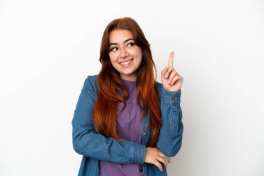 Beyaz arka planda izole edilmiş genç kızıl kadın harika bir fikre işaret ediyor.