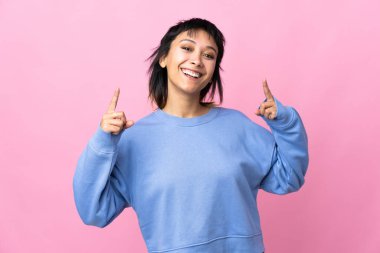 Genç Uruguaylı kadın soyutlanmış pembe arka planda harika bir fikre işaret ediyor.